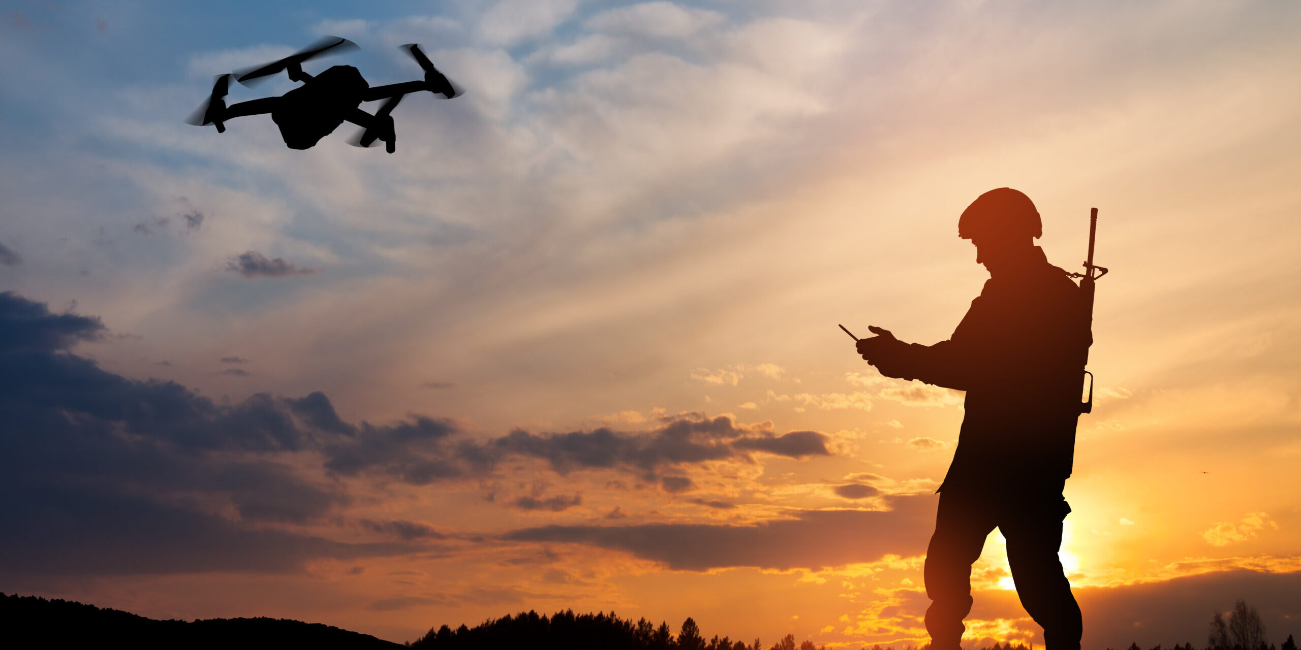 Silhouette of soldier using drone and laptop computer for scouting during military operation.